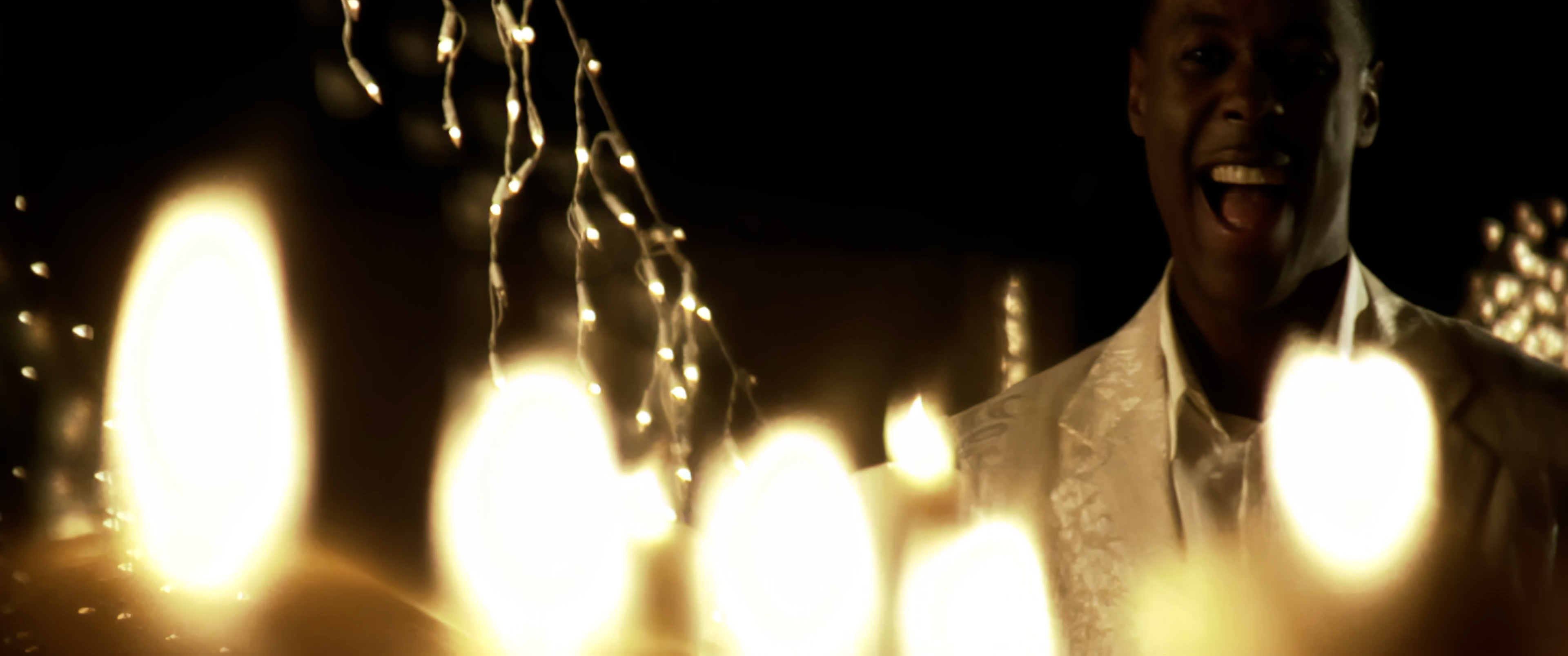 Micah Stampley laughing, close-up with candle bokeh