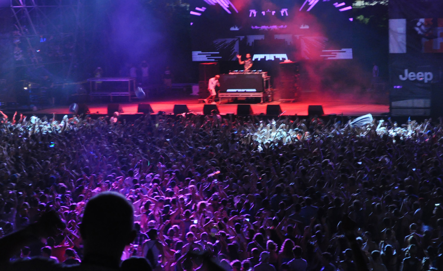 Massive festival crowd at night, purple stage lights