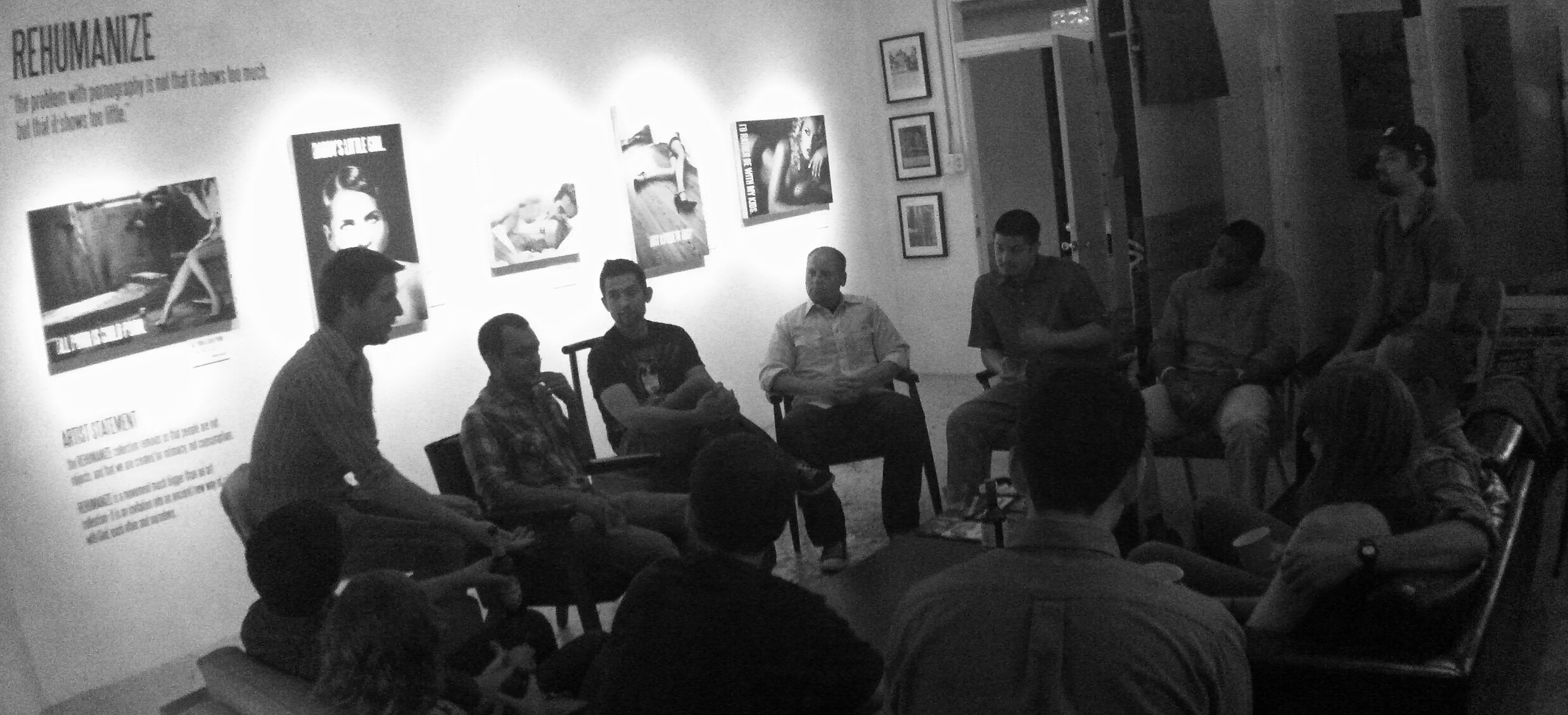 Intimate gallery discussion surrounded by REHUMANIZE canvases